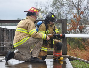 SFSC instructor Eric Hanks works with a recruit on the proper technique for deploying a hose.