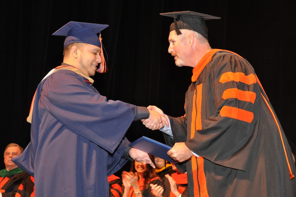 Gus Ramirez received his bachelor's degree diploma from SFSC trustee Derren Bryan.