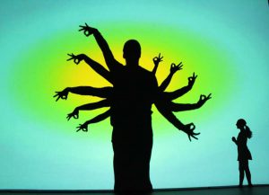 Silhouette from performance of a person with many arms like branches on a tree and a woman looking up at it, photo courtesy of Catapult