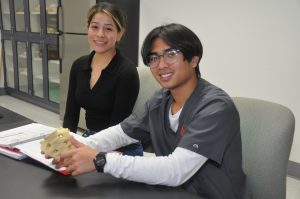 A female student and a male student holding a model.