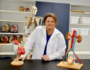 Carol Mitchell in a lab coat with organ models.