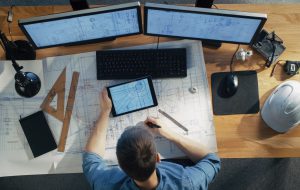 A person studying blueprints and screens for drafting. 