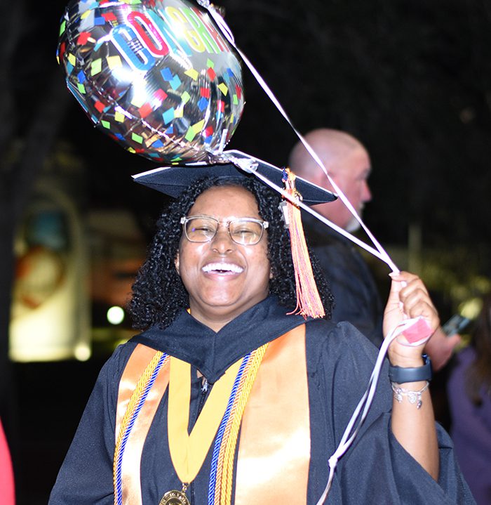 Graduate holding balloons