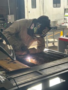 Student with mask on using welding tools to make sparks fly.