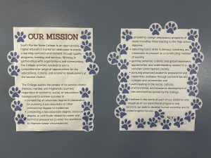 Two posters with paw print stickers all over them.