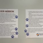 Two posters with paw print stickers all over them.
