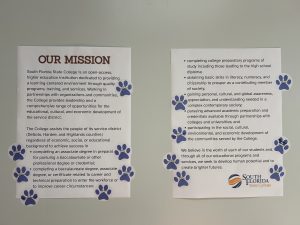 Two posters with paw print stickers all over them.