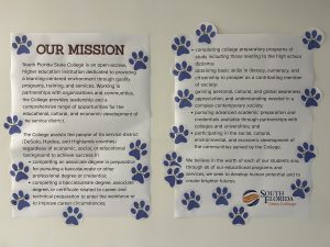 Two posters with paw print stickers all over them.