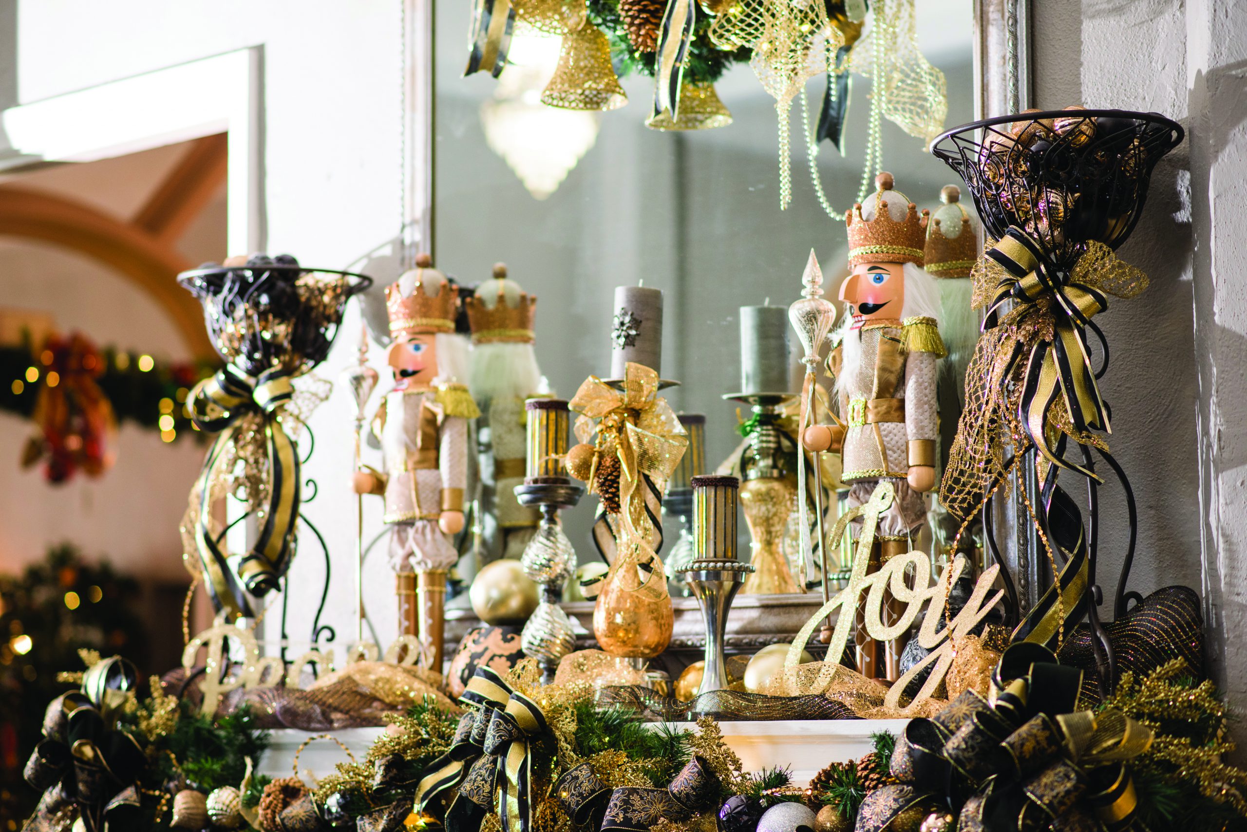 A mantle decorated for the holidays with nutcrackers, candles, and the word "joy" in gold.