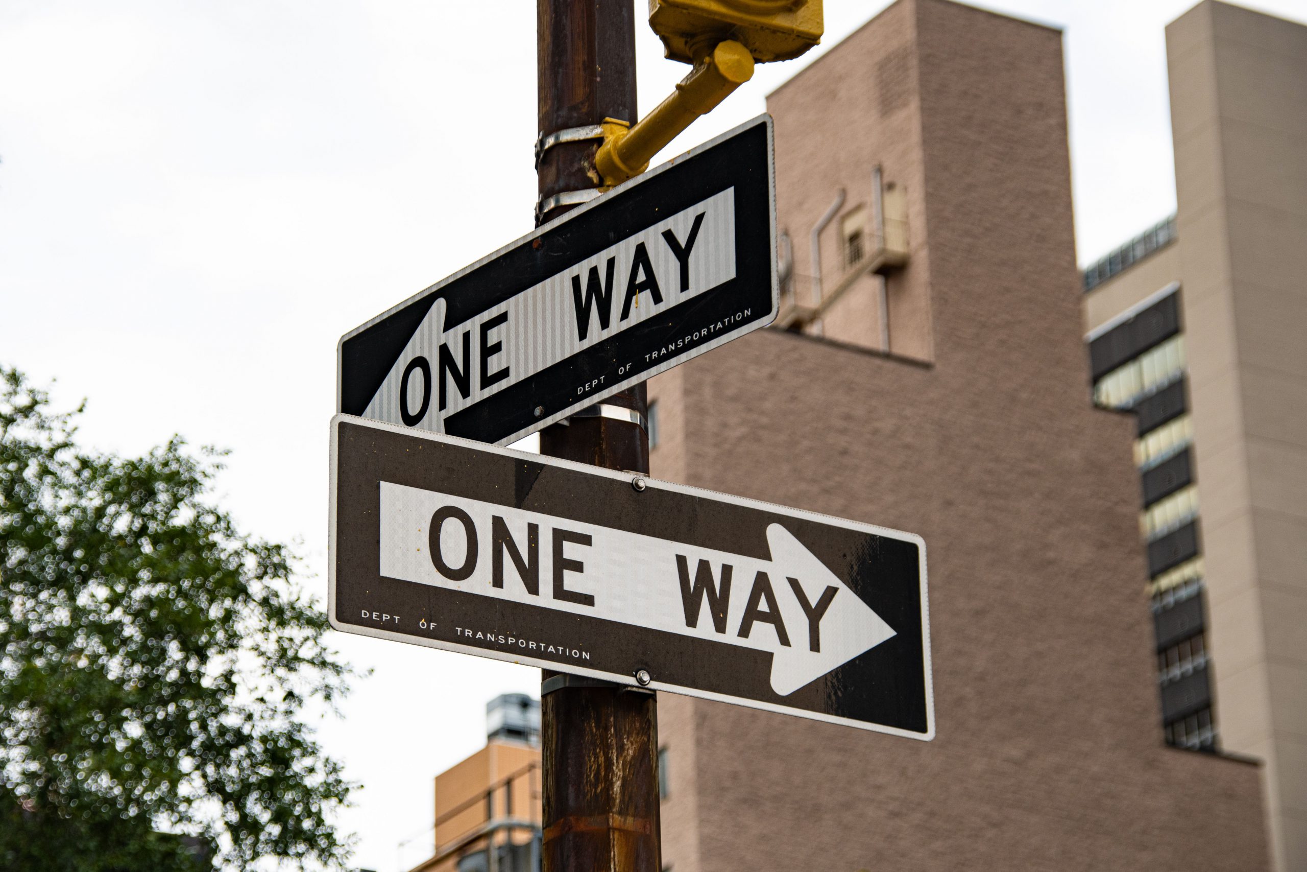 Two one way signs on a pole on a street.